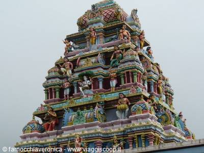 Hindu temple gopuram covered in colorful deity statues, grey sky