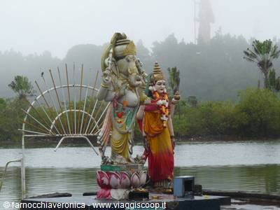Ganesha and Hanuman statues on a lake, misty green trees