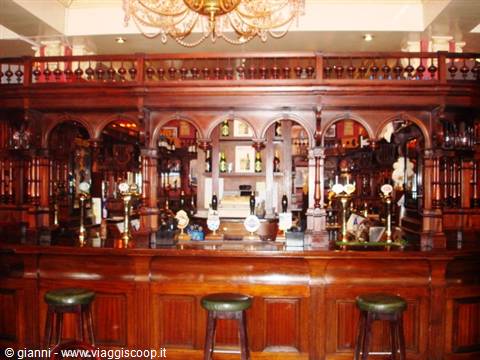 Carved wooden counter of a Victorian pub with beer taps and stools