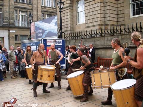Drummers in kilts perform for passersby on a Glasgow street