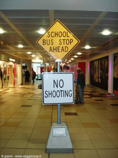 Yellow school bus and no shooting signs on pole inside lit shopping arcade