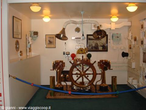 Brass ship wheel and nautical instruments displayed in a lit museum room
