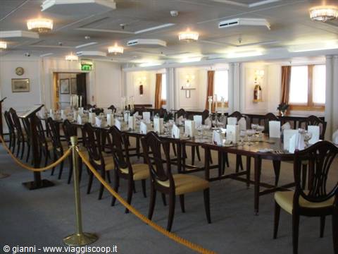 Dining room with long set table, upholstered chairs and illuminated chandeliers