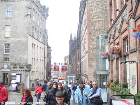 Tourists walking down the Royal Mile among old stone buildings and flowers