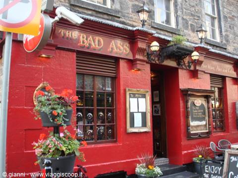 The Bad Ass pub in Edinburgh, red facade with flowers and lit lanterns