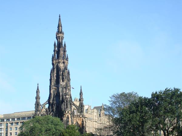 The Gothic Scott Monument in dark stone, Edinburgh, under a blue sky