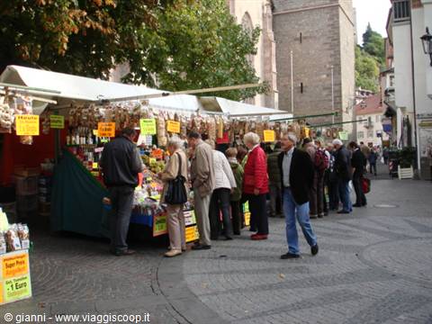 Street market under white canopies, people queue at stalls