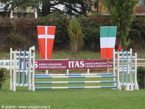 Equestrian jump obstacle with Danish and Italian flags on green field