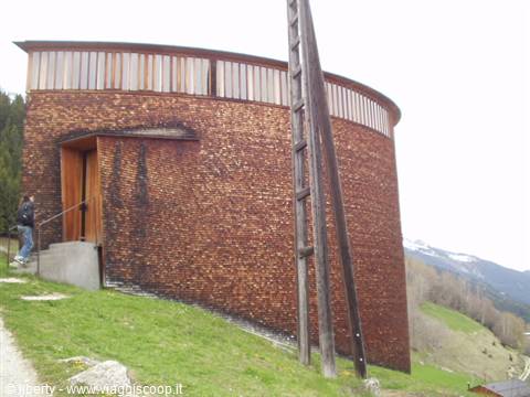 Saint Benedict Chapel in Sumvitg, curved shingled timber chapel on a green hillside