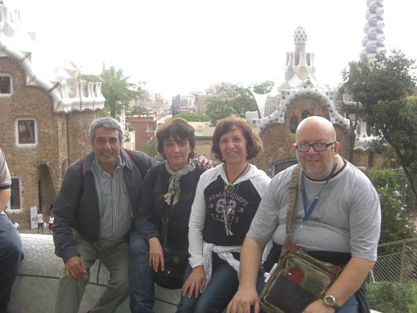Four people sit in front of Gaudí's stone houses at Park Güell
