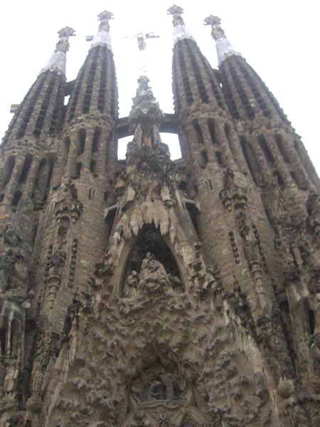 Carved stone facade of the Sagrada Família in Barcelona, towers against pale sky