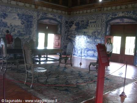 Room with blue azulejo tiled walls, antique table and wooden chairs