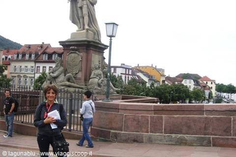 Smiling woman beside the stone statue on Heidelberg's Old Bridge