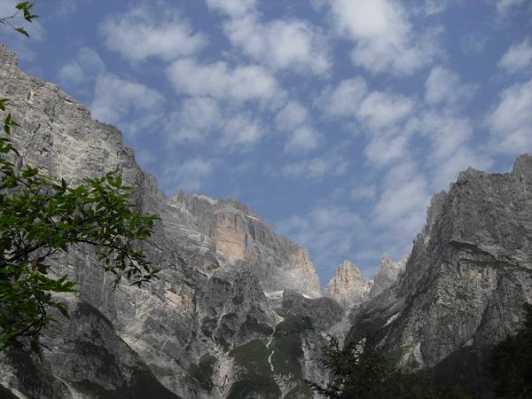 Steep rock walls rising above the valley, blue sky with white clouds