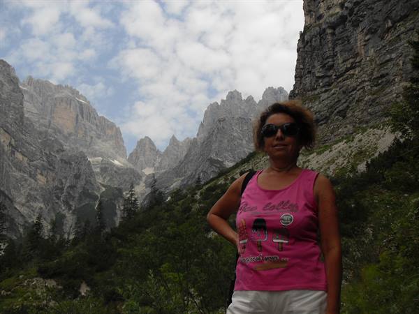 Woman in pink tank top and sunglasses before rocky Dolomite peaks