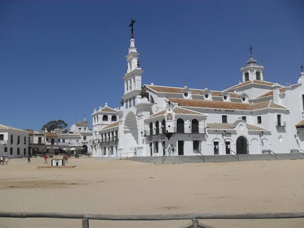 Hermitage of El Rocío, white facade with bell tower, few visitors on the sand