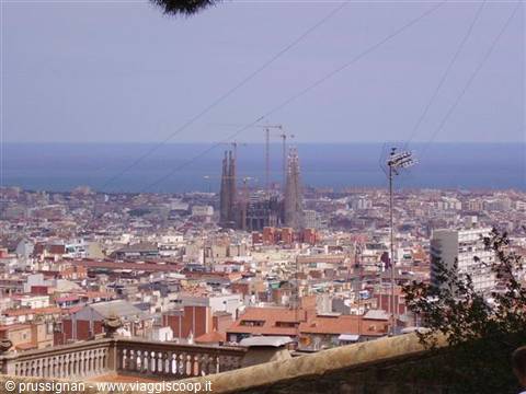 Sagrada Família with cranes above Barcelona rooftops and the sea