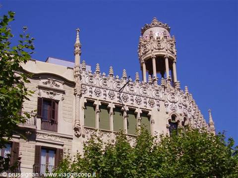 Ornate modernist facade with spires and turret under blue sky, Barcelona