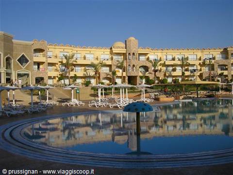 Pool with umbrellas and loungers in front of a yellow Arabian-style resort