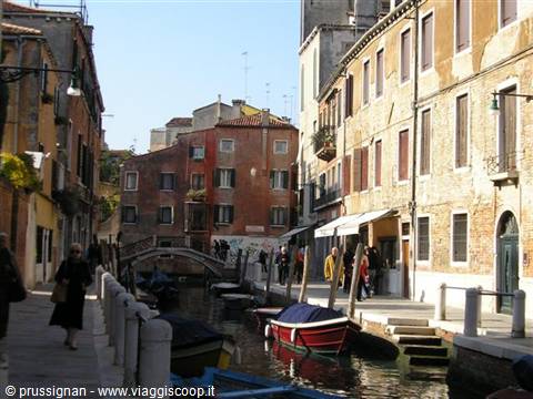 Venice canal with covered boats, small bridge and colorful old houses