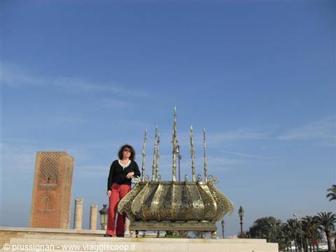 Woman beside a large golden brazier at the Hassan Tower in Rabat