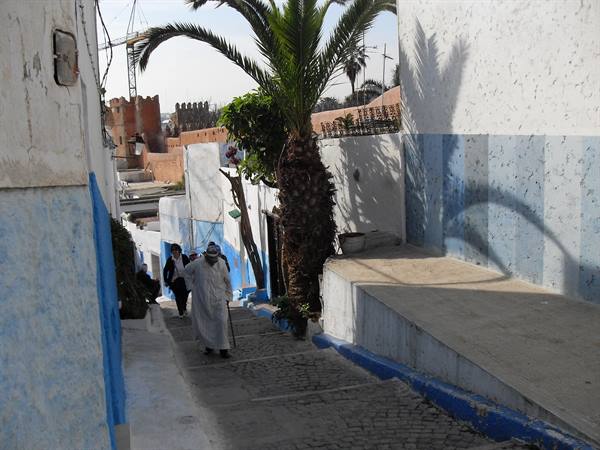 Man in white djellaba walking blue-and-white alley stairs, Kasbah of the Udayas