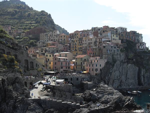 Manarola, Cinque Terre: colorful houses on the cliff, tourists near boats