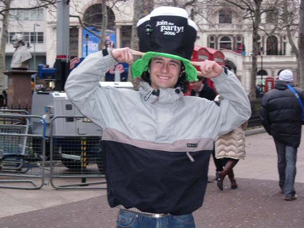 Smiling young man wearing an oversized black and green hat in a city square