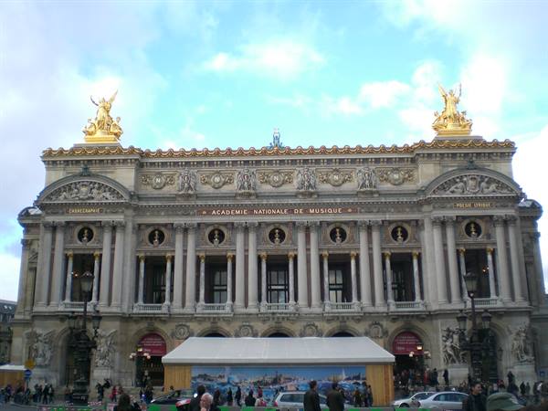 Facade of the Palais Garnier in Paris, golden statues, tourists under the tent