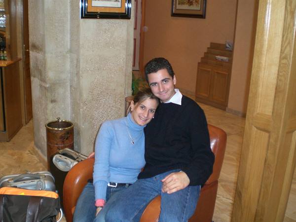 Smiling couple on leather armchair in hotel lobby, luggage nearby