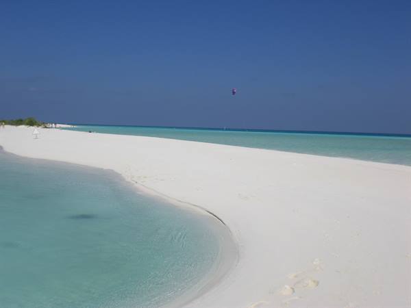 Long white sand spit between turquoise waters, kite flying above