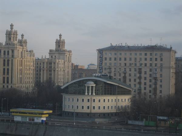 Stalinist towers and curved-roof rotunda building in Moscow under grey light