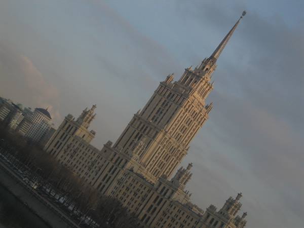 Stalinist skyscraper with spire rising over the river, golden light, Moscow