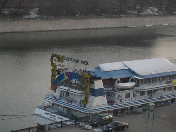 River cruise ship Aleksandr Radishchev moored, snow on deck, cars parked on embankment
