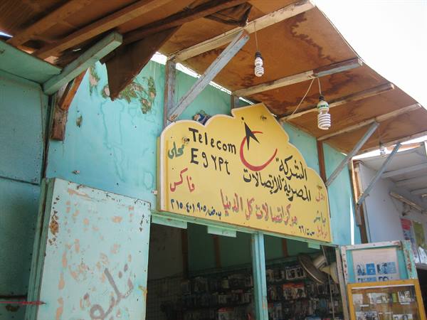 Yellow Telecom Egypt sign on a small shop with turquoise walls, hanging bulbs