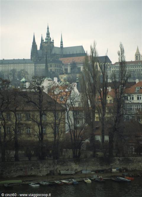 Prague Castle and St Vitus Cathedral above trees and boats on the Vltava