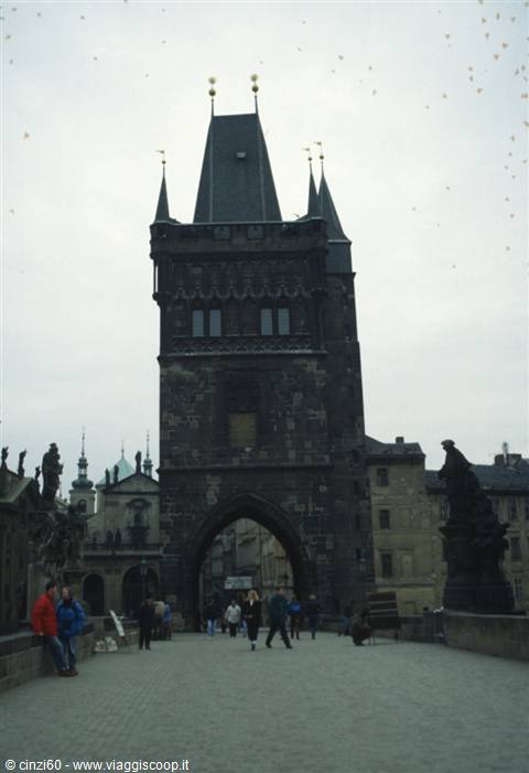 Tourists walk beneath the Gothic Old Town Bridge Tower on Charles Bridge, Prague