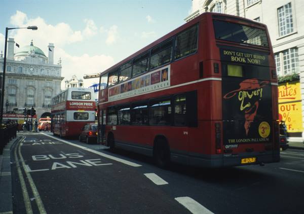 Red double-decker buses on bus lane near London Palladium, daylight