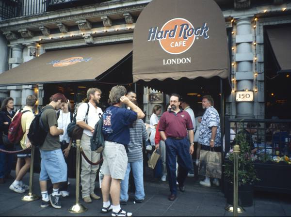 Tourists queuing under the brown awning of the Hard Rock Cafe in London