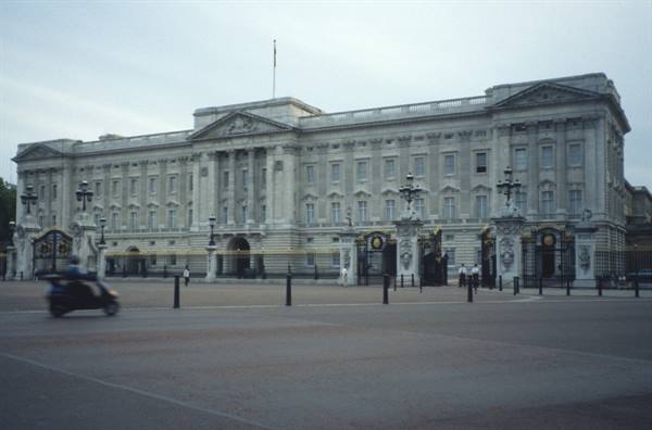 Buckingham Palace in pale stone, a blurred motorbike passes through the empty square