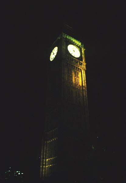 Big Ben lit up at night, white clock face against black sky