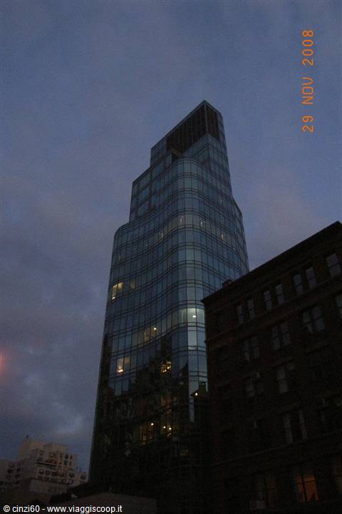Glass skyscraper at dusk beside a dark brick building