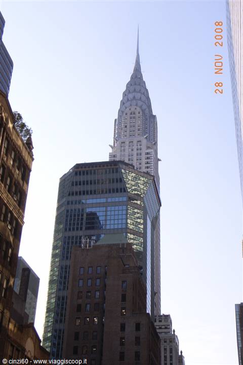 The Chrysler Building towers above surrounding skyscrapers under a clear New York sky