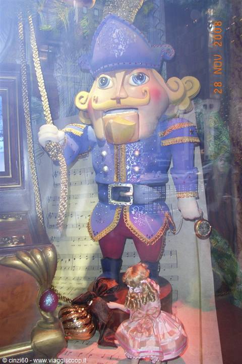 Blue nutcracker statue with golden mustache, shop window decorated with doll and Christmas ornaments