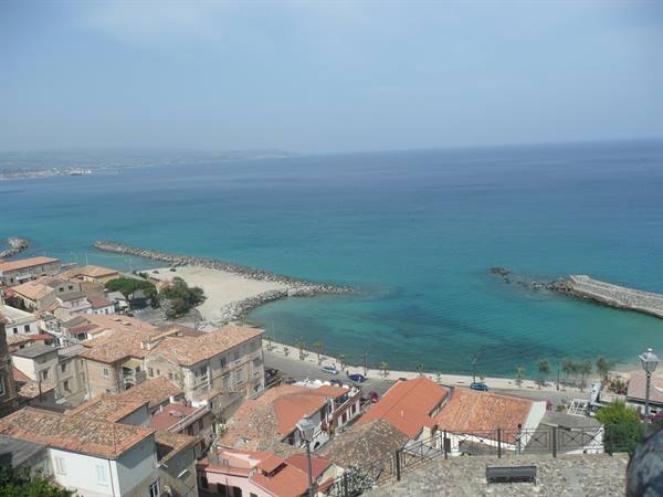 Red rooftops of Pizzo Calabro over turquoise bay, stone piers and beach