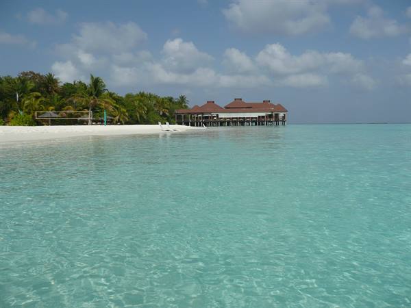 White sand beach with palms and stilt bungalows, clear turquoise water