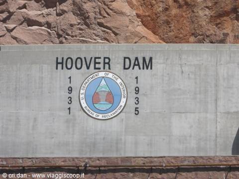 Concrete sign reading Hoover Dam 1931-1935 below a reddish rock wall