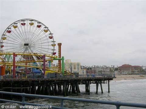 Colorful Ferris wheel and roller coaster on Santa Monica Pier above the ocean