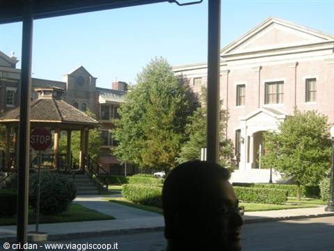 Wooden gazebo and classical brick building seen from bus, passenger silhouette