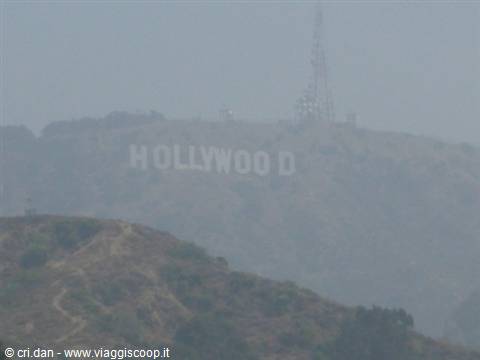 Hollywood sign on the hill, shrouded in haze with a transmission tower